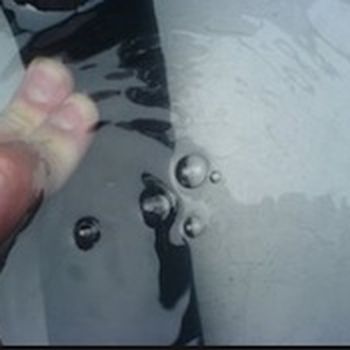 Test seal on a liquid container by filling with pressurised air and immersing in liquid