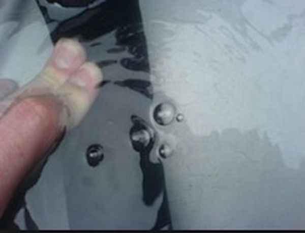 Test seal on a liquid container by filling with pressurised air and immersing in liquid